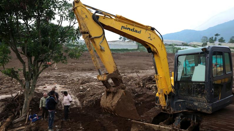 Locals stand beside excavator in an area affected by landslides following heavy rains in Pasir Langu village, West Bandung, West Java province, Indonesia, January 26, 2026. REUTERS/Ajeng Dinar Ulfiana