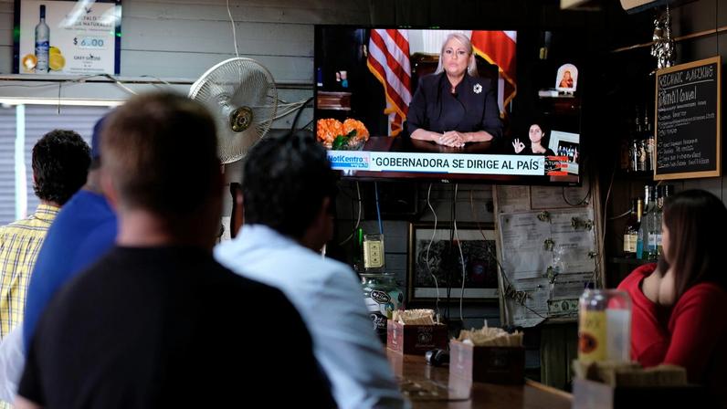 People watch television at a bar as Puerto Rico's Governor Wanda Vazquez Garced makes an address regarding the debt restructuring proposal filed in court by an oversight board, in San Juan, Puerto Rico, September 27, 2019. REUTERS/Ricardo Arduengo