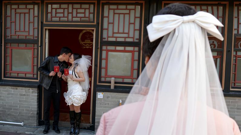 A newlywed couple pose for pictures with their marriage certificates after they registered at the Huguo Guanyin Temple, in Beijing, China, October 28, 2025. REUTERS/Tingshu Wang