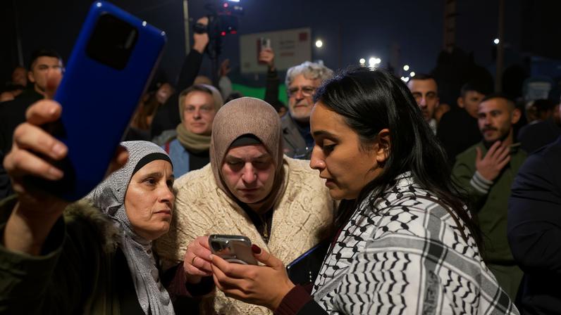 Women look at a mobile phone screen in Ramallah, in the Israeli-occupied West Bank, January 20, 2025. REUTERS/Ammar Awad/File Photo