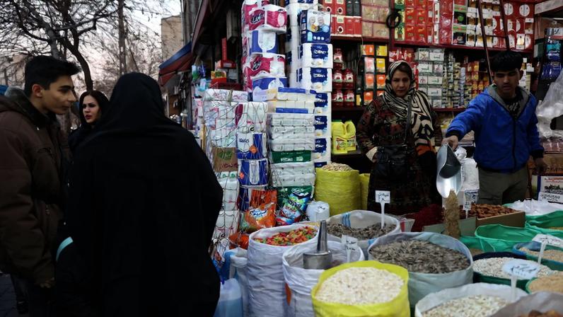 An Iranian woman shops in a local market as protests erupt over the collapse of the currency's value in Tehran