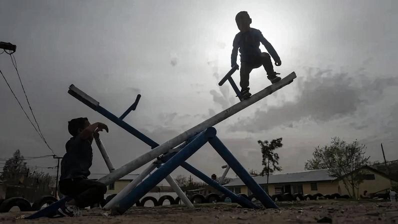 Central American migrant children play on a seesaw at a shelter in Ciudad Juarez, state of Chihuahua, Mexico, on March 21, 2021. US President Joe Biden pushed back on March 25, 2021 against attacks on his handling of a surge of immigrants, calling it a seasonal increase and saying his approach was more humanitarian than predecessor Donald Trump's. The day before, he tasked Vice President Kamala Harris with tackling an influx of migrants on the Mexican border, aiming to take charge of a situation that has energized opponents of the new administration. (Photo by Pedro PARDO / AFP)