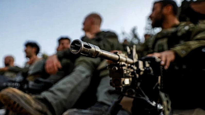 An Israeli army soldier sits by a machine gun deployed on a tripod at a position in the upper Galilee region of northern Israel near the border with Lebanon on October 28, 2023.