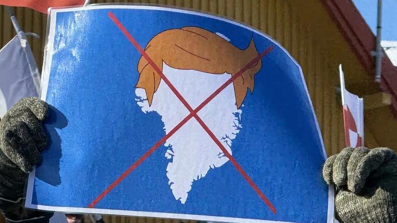A protester holds up a sign depicting U.S. President Donald Trump’s signature hair atop the outline of Greenland during a demonstration near the U.S. Consulate building outside Nuuk, Greenland.