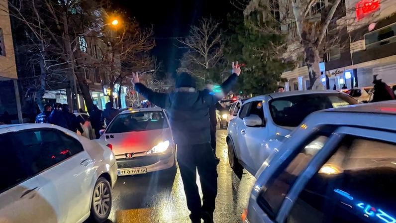 A protester flashes victory signs as traffic slows during demonstrations in Hamedan, Iran, on January 1, 2026.