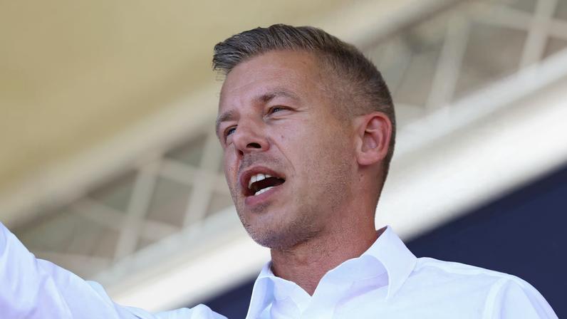 Peter Magyar, leader of the opposition Tisza party, waves a Hungarian flag at a rally near the venue of ruling Fidesz party closed doors meeting where Prime Minister Viktor Orban discusses campaign issues with party officials in Kotcse, Hungary September 7, 2025. REUTERS/Bernadett Szabo/File Photo