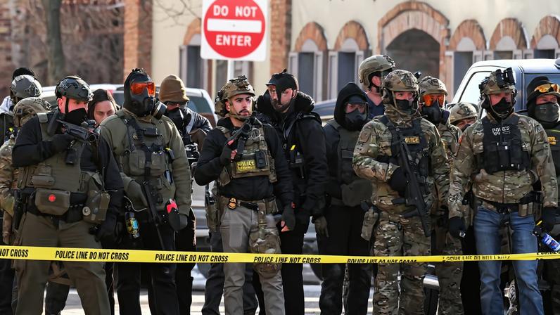 Federal agents stand behind police tape as demonstrators gather near the site of where state and local authorities say a...