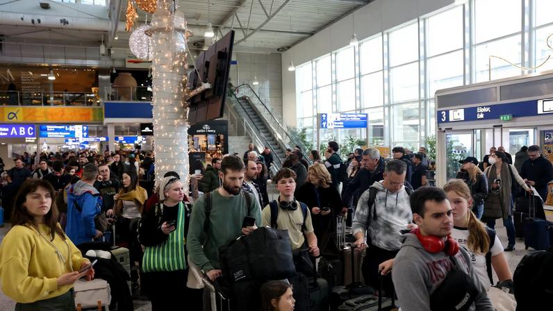 People stand with their luggage, as airports across Greece have suspended arrivals and departures on Sunday, after unspecified issues affecting radio frequencies, at the Eleftherios Venizelos International Airport, in Athens