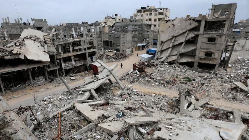 Palestinians walk surrounded by the rubble of houses destroyed in Israeli strikes during the war, in Khan Younis