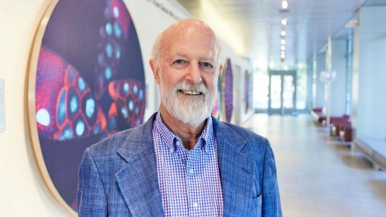 Richard Hynes in a gallery with large research images in back