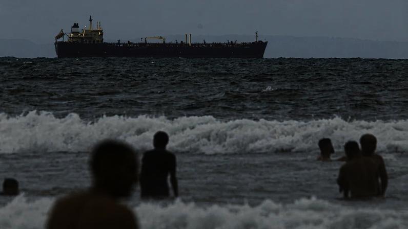 People enjoy the ocean near the Comoros-flagged oil tanker Evana, used to move oil between domestic ports in Venezuela, near El Palito terminal, in Puerto Cabello, Venezuela December 29, 2025. REUTERS/Juan Carlos Hernandez