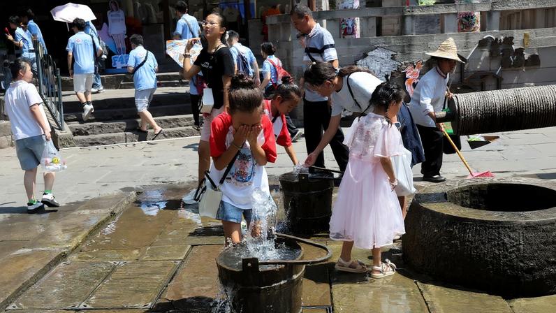 A child rinses her face with water amid a red alert for heat in Chongqing