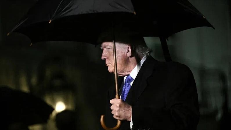 Donald Trump holds an umbrella.