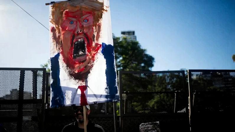 A man holds a painting depicting U.S. President Donald Trump during a protest against U.S. intervention in Venezuela, in Buenos Aires.