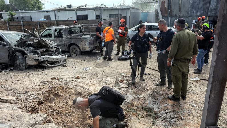 A security official investigates the crater formed when a projectile landed, after Hamas' armed wing said it attacked Tel Aviv with a missile salvo, amid the ongoing Israel-Hamas conflict, in Kfar Chabad