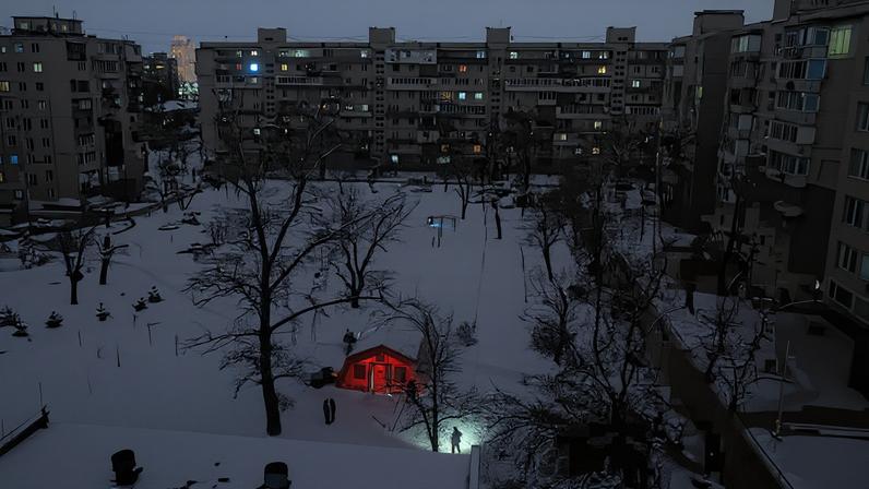 A person carrying a torch approaches a tent provided by emergency services for residents whose apartments are left without heating during sub-zero temperatures, amid Russia's attack on Ukraine, during a winter night in Kyiv, Ukraine, January 17, 2026.