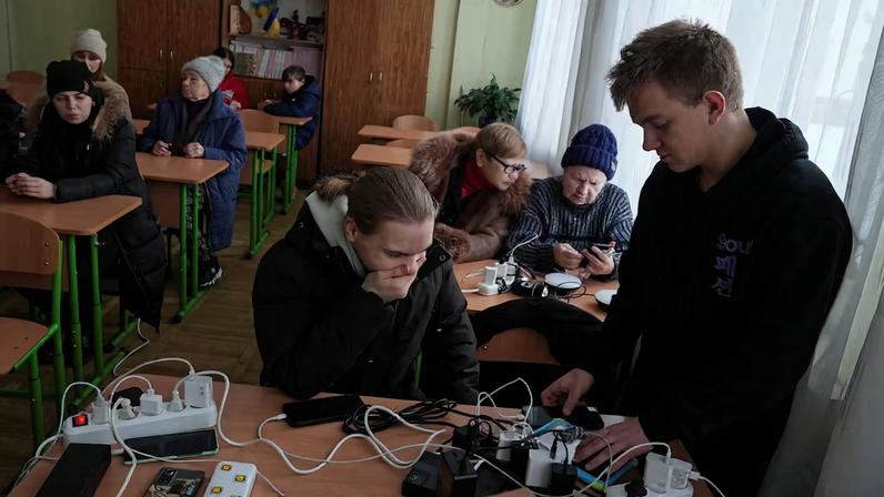 Residents charge theirdevices inside a school classroom turned into a humanitarian aid point during a power blackout in Kyiv