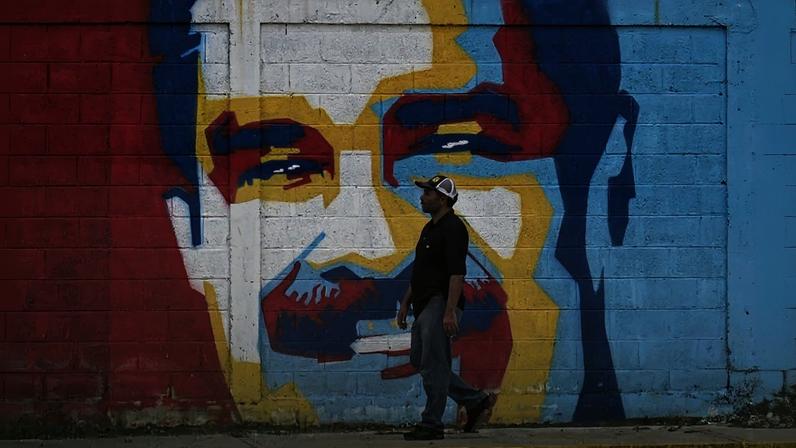 A man walks past a mural depicting Venezuelan President Nicolás Maduro in Caracas.