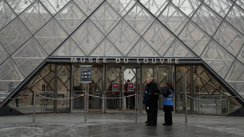 Employees stand in front of the glass Pyramid of the Louvre Museum whose opening has been postponed during a staff meeting about a strike over pay and working conditions at the museum, the state of the museum's buildings and staffing issues, after a spectacular heist which saw thieves make off with jewels in broad daylight, in Paris, January 5, 2026.