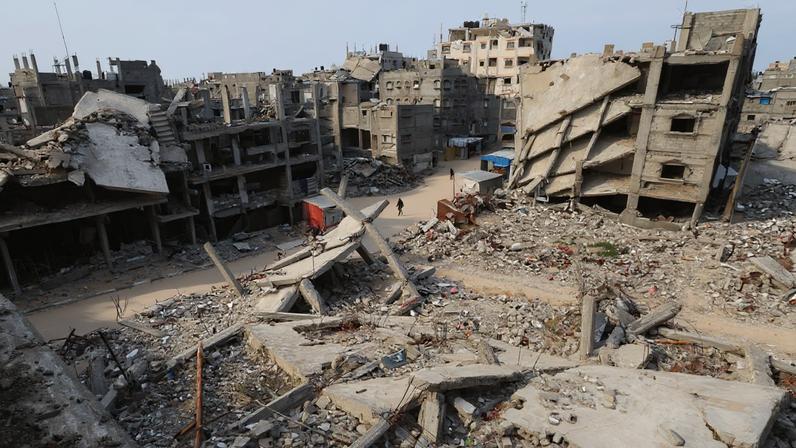 Palestinians walk surrounded by the rubble of houses destroyed in Israeli strikes during the war, in Khan Younis, southern Gaza Strip, January 22, 2026. REUTERS/Ramadan Abed