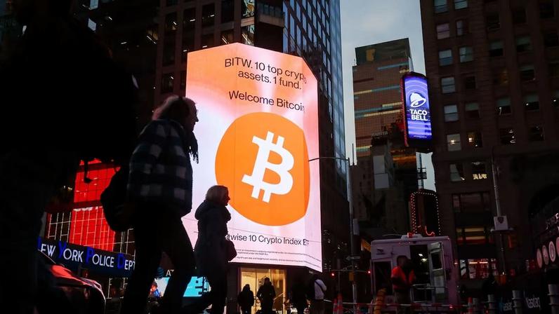 Bitcoin signage in Times Square in New York, US, on Tuesday, Dec. 9, 2025. The market is still reeling from a flash crash on Oct. 10 that saw more than $19 billion of crypto bets liquidated, and spot trading volumes have fallen 66% since their January highs.