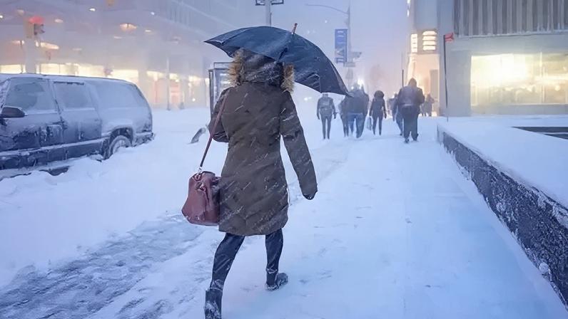 Getty Images A person walks into the snow with an umbrella and their back to the camera on a snowy street in the United States.