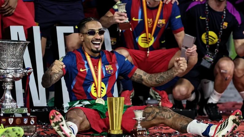 Raphinha ao lado da taça da Supercopa da Espanha e com o troféu de MVP do jogo — Foto: FADEL SENNA/AFP