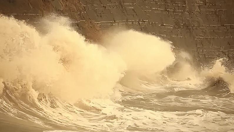 Waves break against Church Cliff Walk in Lyme Regis, which has a flood warning for the harbour on Friday evening