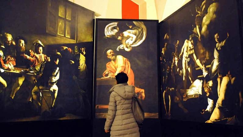 Mulher observa reproduções digitais das obras de Caravaggio, em 2013 caravaggio pintura barroco