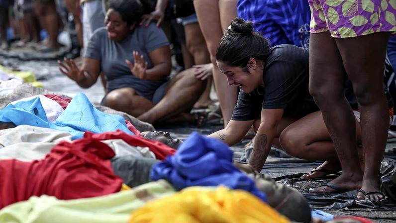 Moradores levam corpos de suspeitos mortos para reconhecimento de famílias em praça no Complexo da Penha (Foto: André Coelho/EFE)