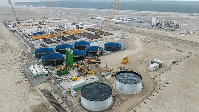 Haventus Construction at Ardersier Port. The site is flat and sandy and there are a number of large structures including circular tanks.