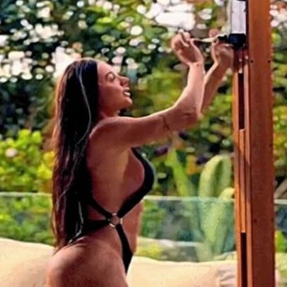 Juju Salimeni surge na beira da piscina com guarda-sol gigante