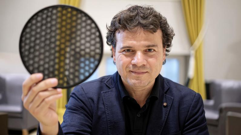 Pablo Jarillo-Herrero holds a translucent black disk comprised of hexagonal cells