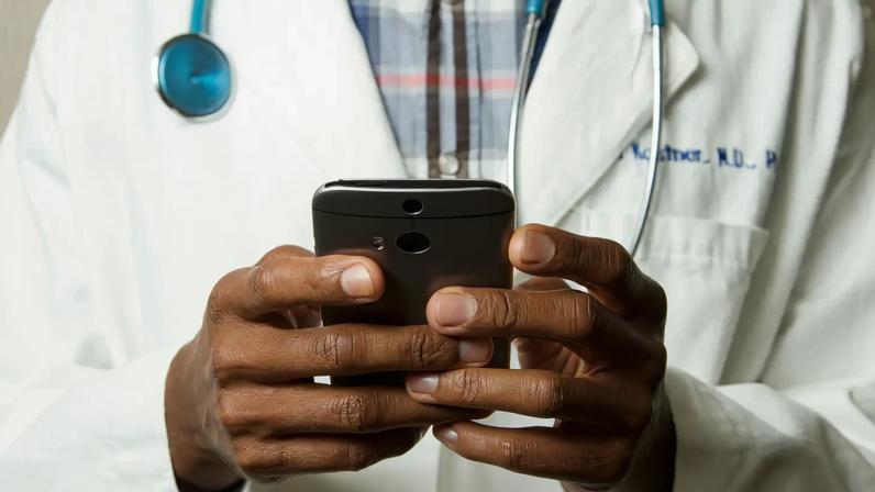 Médico com estetoscópio fala no celular. Foto: National Cancer Institute/Unsplash