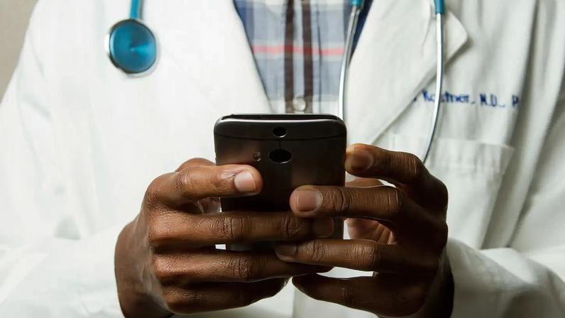 Médico com estetoscópio fala no celular. Foto: National Cancer Institute/Unsplash