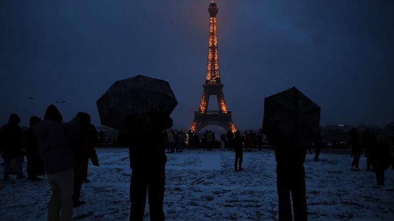 Pessoas se abrigam sob guarda-chuvas na praça do Trocadero, coberta de neve, perto da Torre Eiffel, em Paris 05/01/2026 REUTERS/Abdul Saboor