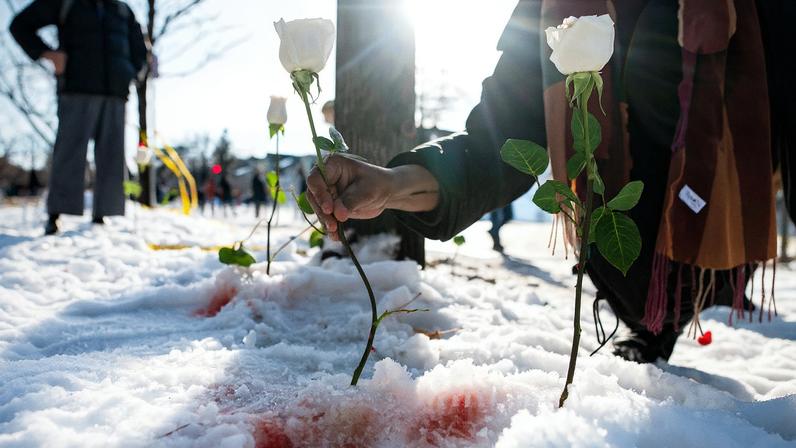 A person places a flower at the site where Renee Nicole Good was shot and killed by ICE agent Jonathan Ross during federal law enforcement operations on January 7, 2026, in Minneapolis.