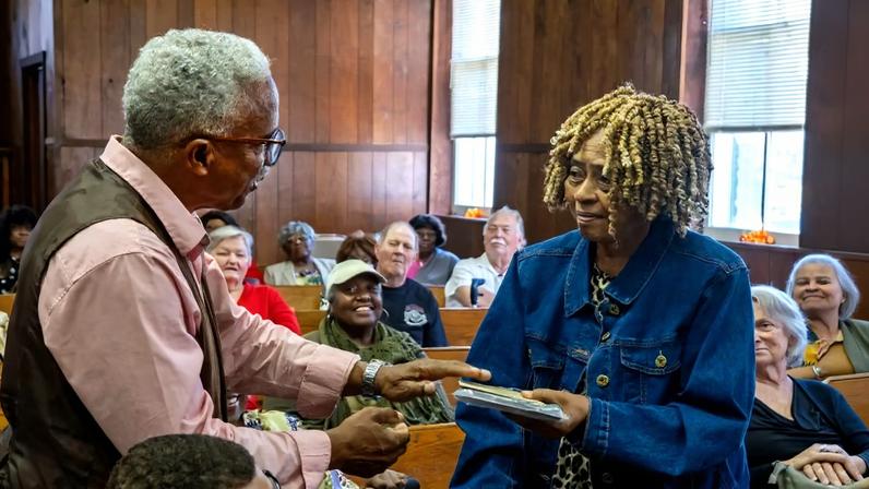 Silver Point reunion committee chair Harold Carr awards a commemorative plaque to Geraldine Tibbs, honoring her decades of work in organizing the Silver Point homecoming.