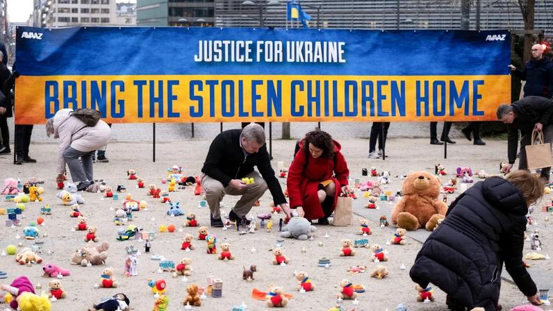 People from the nonprofit organization, AVAAZ, light candles in Belgium beside teddy bears for Ukrainian children who have been kidnapped.