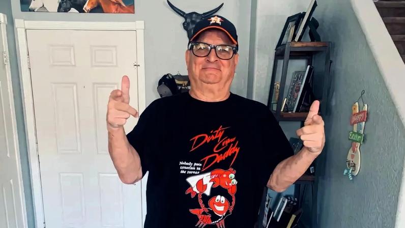 Sean Swayze wearing a "Dirty Craw Daddy" t-shirt and an Astros baseball cap, posing with finger guns.