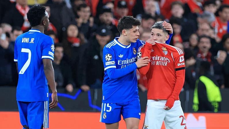 O atacante argentino do Benfica, número 25, Gianluca Prestianni, cobre a boca enquanto discute com o atacante brasileiro do Real Madrid, número 7, Vinicius Junior, que se queixou de supostos insultos racistas durante o jogo de ida da fase eliminatória da Liga dos Campeões. Foto: PATRICIA DE MELO MOREIRA / AFP