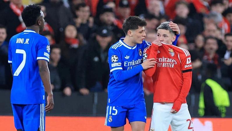 O atacante argentino do Benfica, número 25, Gianluca Prestianni, cobre a boca enquanto discute com o atacante brasileiro do Real Madrid, número 7, Vinicius Junior, que se queixou de supostos insultos racistas durante o jogo de ida da fase eliminatória da Liga dos Campeões. Foto: PATRICIA DE MELO MOREIRA / AFP