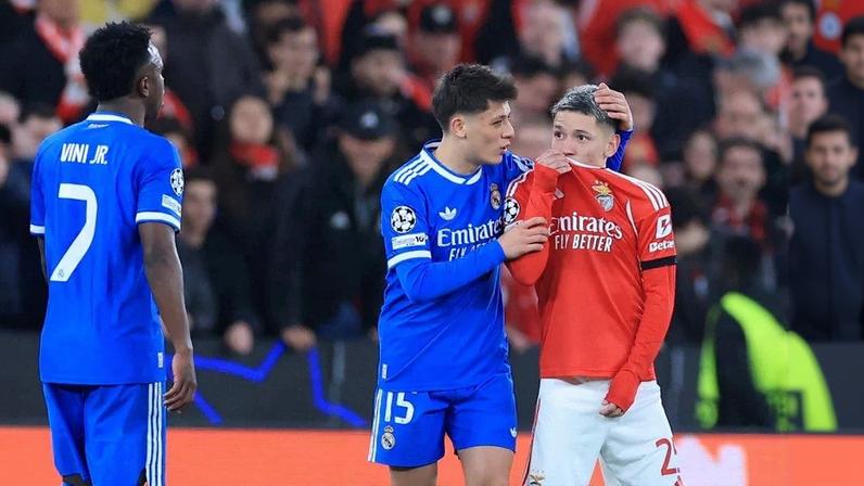 O atacante argentino do Benfica, número 25, Gianluca Prestianni, cobre a boca enquanto discute com o atacante brasileiro do Real Madrid, número 7, Vinicius Junior, que se queixou de supostos insultos racistas durante o jogo de ida da fase eliminatória da Liga dos Campeões. Foto: PATRICIA DE MELO MOREIRA / AFP