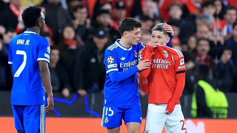 O atacante argentino do Benfica, número 25, Gianluca Prestianni, cobre a boca enquanto discute com o atacante brasileiro do Real Madrid, número 7, Vinicius Junior, que se queixou de supostos insultos racistas durante o jogo de ida da fase eliminatória da Liga dos Campeões. Foto: PATRICIA DE MELO MOREIRA / AFP