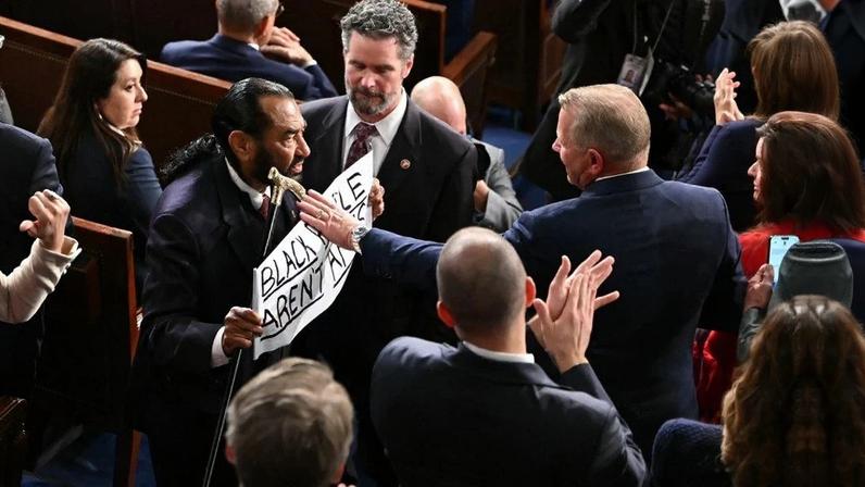 O deputado americano Al Green, democrata pelo Texas, segura uma placa com os dizeres "Pessoas negras não são macacos" enquanto o presidente dos EUA, Donald Trump, discursa sobre o Estado da União na Câmara dos Representantes do Capitólio dos EUA em Washington, DC, em 24 de fevereiro de 2026. Foto: ANDREW CABALLERO-REYNOLDS / AFP