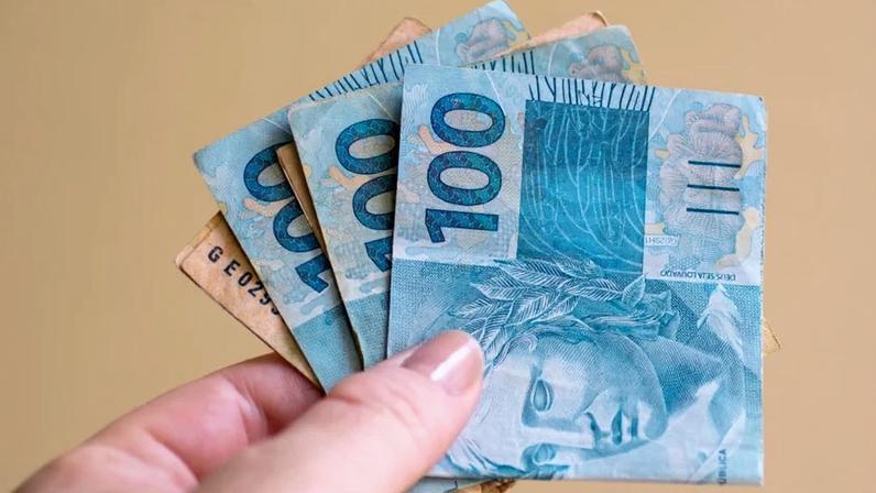 Mão segura notas de cem reais