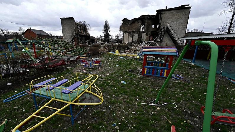 A destroyed multicolored playground with a destroyed building in the background.