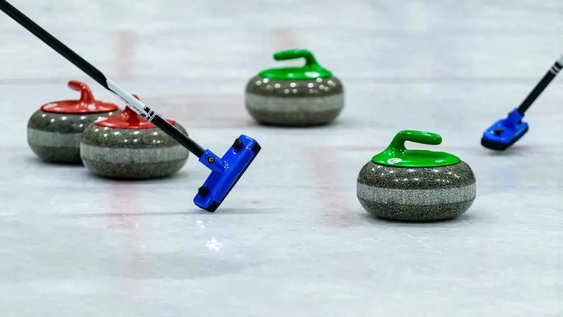 Imagem de pedras de curling na pista de gelo.