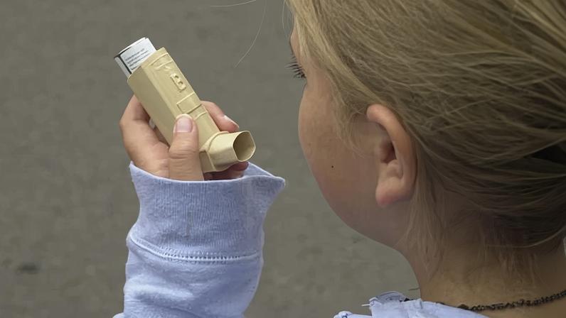 Young girl using asthma inhaler.