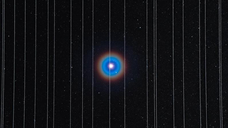 A imagem de fundo mostra a estrela dupla Albireo, na constelação de Cisne, e foi capturada em 26 de dezembro de 2019. Duas das dez exposições de 2,5 minutos registraram satélites Starlink se movendo pelo campo de visão.